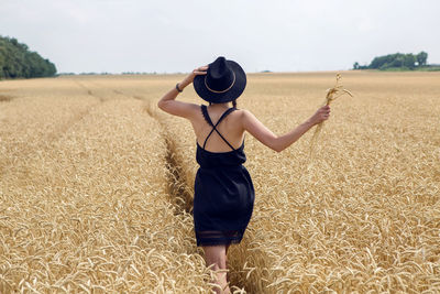 Woman in a black dress and a hat running