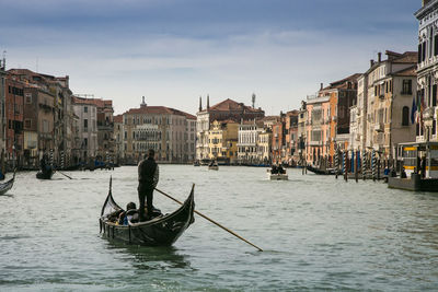 Man in gondola on canal against buildings