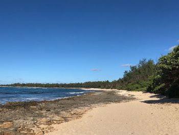 Scenic view of beach against clear blue sky