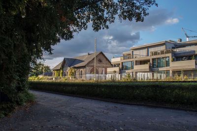 Houses on field by buildings against sky