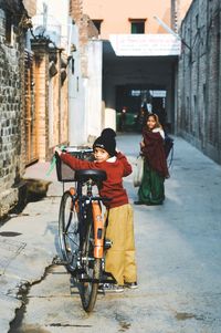 Portrait of boy with bicycle standing at alley