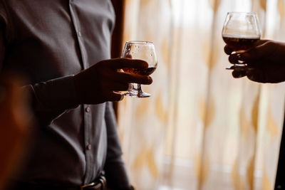 Men with a friend standing by the window. hold in the hands of glasses of whiskey.