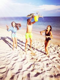 Siblings playing on beach against sky