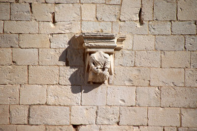 Close-up of statue against brick wall