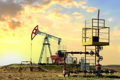 Traditional windmill on field against sky during sunset