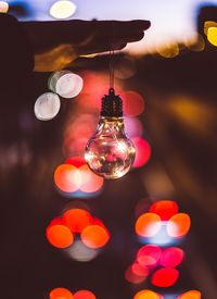 Close-up of hand holding illuminated light bulb