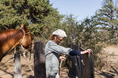 Smiling woman with horse standing at farm