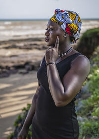 African woman with headdress looks out to sea during sunset in west africa ghana