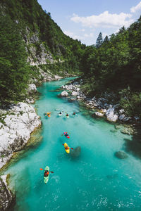 High angle view of people kayaking in lake amidst mountain