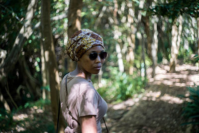 Portrait of mid adult woman standing in forest during sunny day