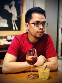 Portrait of young man with cocktails on table at restaurant