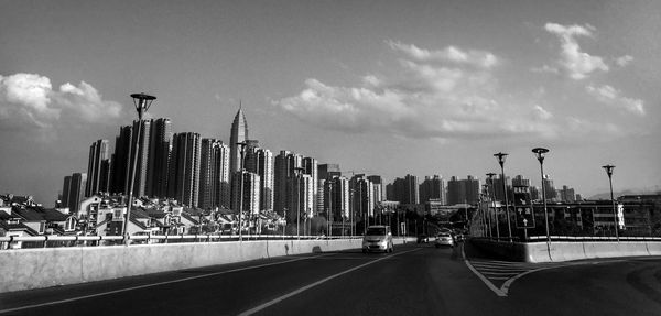 Cars moving on road amidst buildings against sky