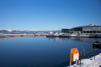 Boats moored at harbor against clear blue sky