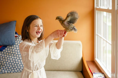 A laughing child with missing tooth holds a flapping bird aloft