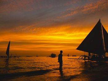 Silhouette man on beach against sky during sunset