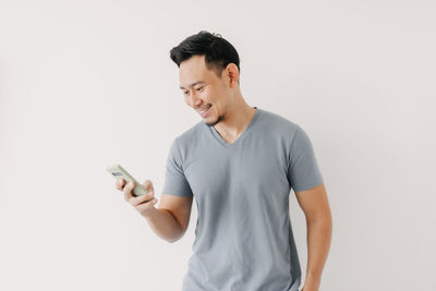 Young man using mobile phone against white background