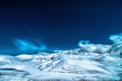 Scenic view of snow covered landscape against blue sky