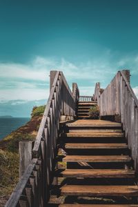 Staircase leading towards sea against sky