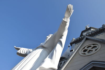 Low angle view of statue against building against clear blue sky