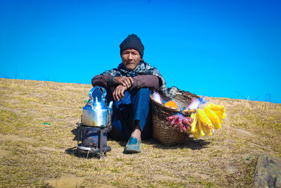 Full length portrait of man standing on field against clear blue sky