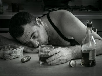 Close-up of man drinking whiskey on table