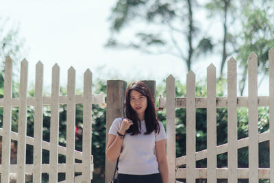 Portrait of woman standing against fence