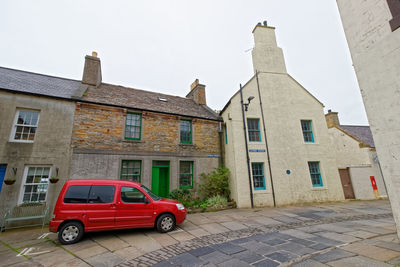 Car on street by buildings against sky