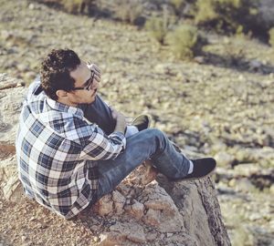 High angle view of mid adult man sitting on cliff