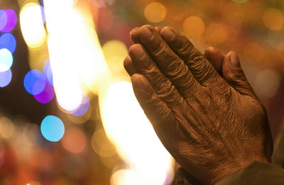 Close-up of hand against illuminated blurred background