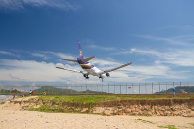 Airplane flying over land against sky