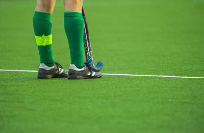 Low section of player playing hockey on field