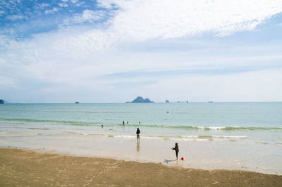 People standing on beach against sky