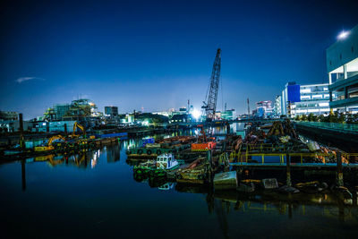 Illuminated harbor by river against sky at night