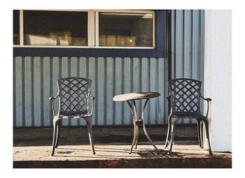 Empty chairs and table against building