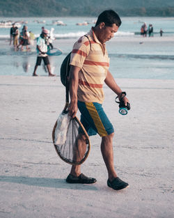 Full length of young man looking at camera on beach