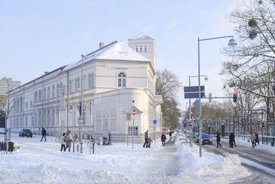 People on street by buildings in city against sky