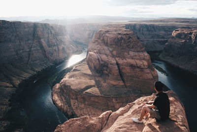 Man sitting on rock formations by horseshoe bend
