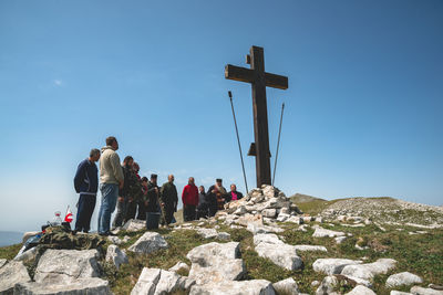 People on rocks against clear sky