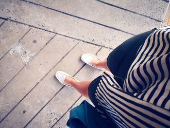 Low section of woman sitting on footpath