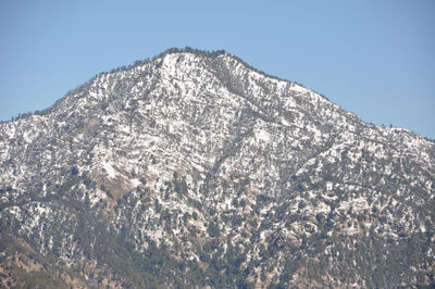 Low angle view of snowcapped mountain against clear blue sky