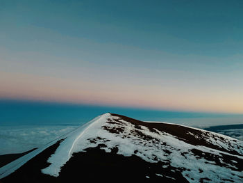 Scenic view of snow covered land and sea against sky during sunset