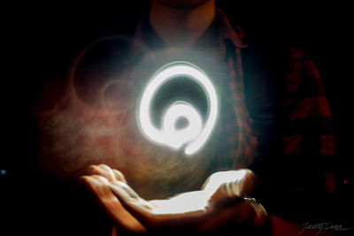 Close-up of human hand against illuminated light