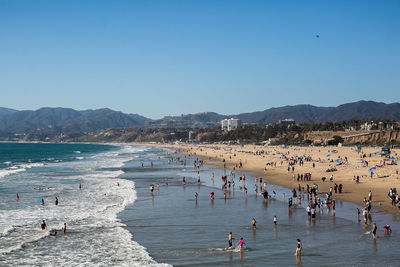 People on beach against clear blue sky