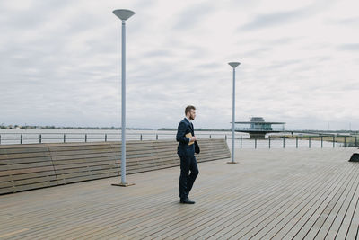 Man standing on pier over sea against sky