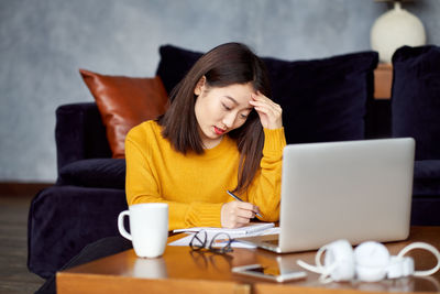 Young woman using mobile phone while sitting on table