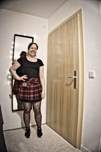 Portrait of young woman standing against door at home