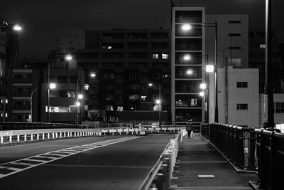 Empty road along buildings at night