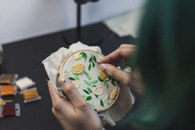 Young woman's hands embroidering cloth in shape of lemon tree