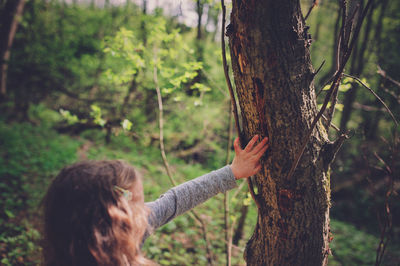 Woman with tree trunk in forest