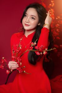 Portrait of young woman holding red flower